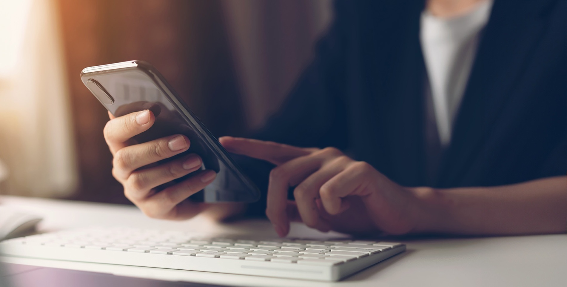 una persona sostiene un teléfono inteligente y presiona un botón en un teclado