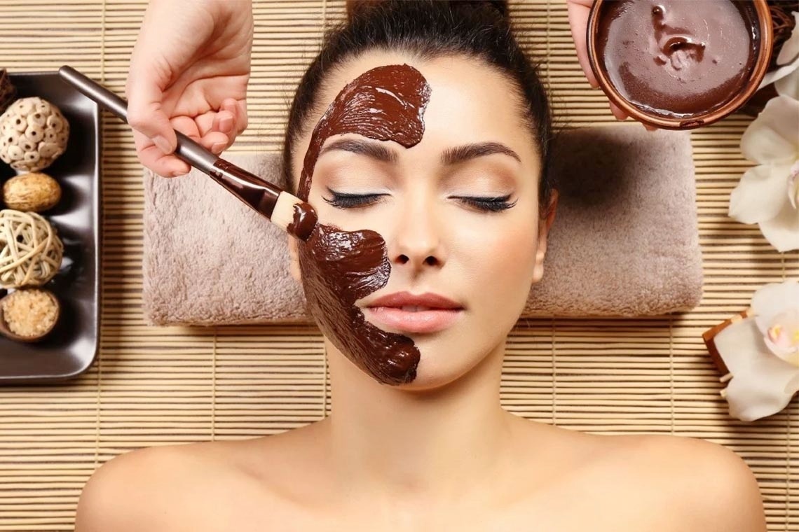 a woman is getting a chocolate mask on her face