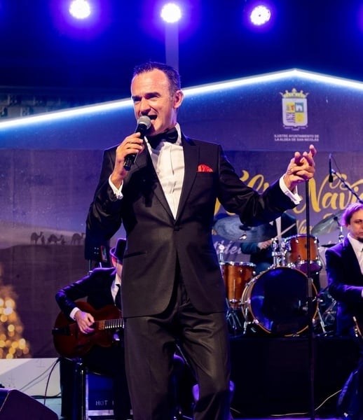 a man in a tuxedo is singing into a microphone