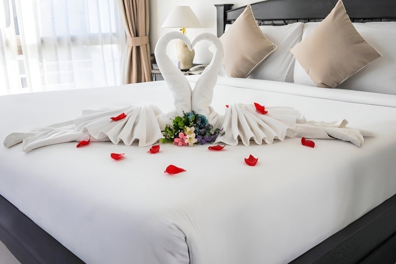 una cama con dos cisnes hechos de toallas y pétalos de rosa