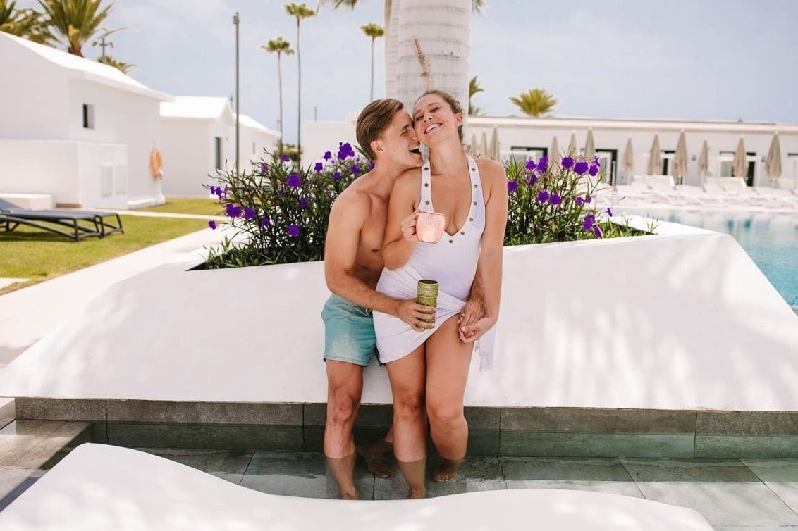 a man kisses a woman on the cheek while holding a drink