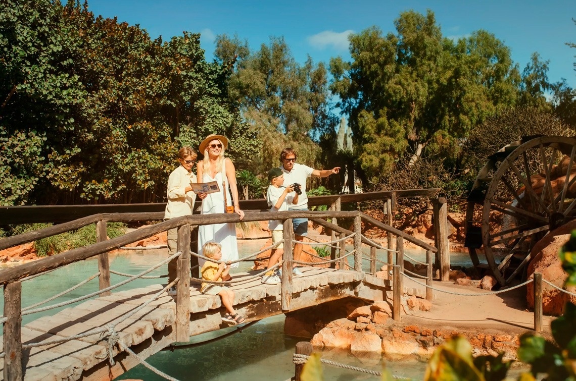 a family crosses a wooden bridge over a body of water