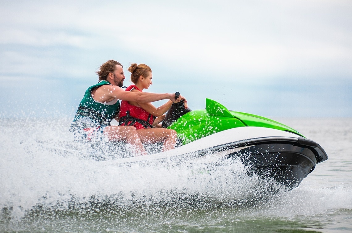 a man and a woman are riding a green and white jet ski