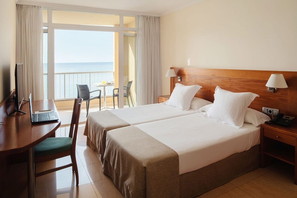 a hotel room with two beds and a desk with a laptop on it