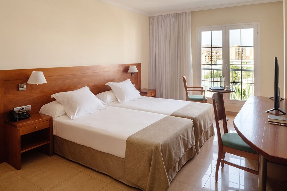 a hotel room with two beds a desk and a television