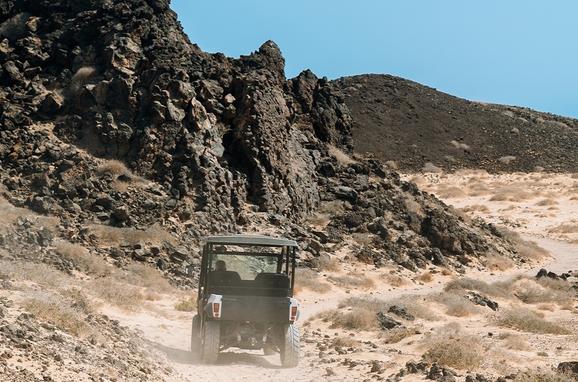 a jeep is driving down a dirt road in the desert