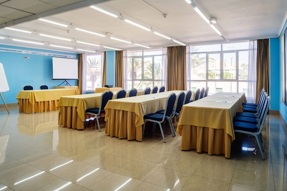 una sala de conferencias con mesas y sillas y una pantalla