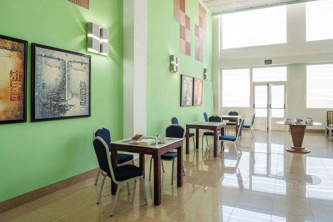 a room with tables and chairs and a green wall