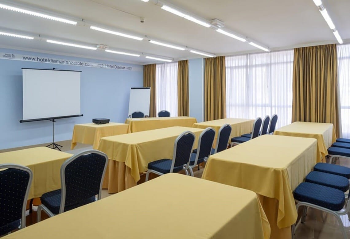 a conference room with tables and chairs and a projector screen