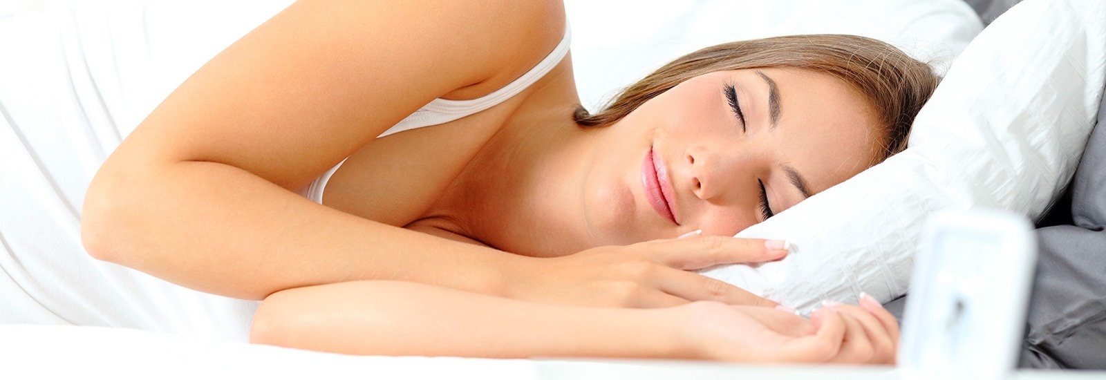 una mujer duerme en una cama con los ojos cerrados