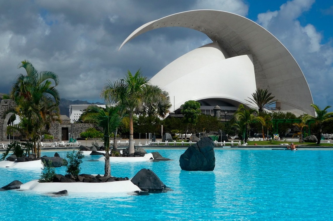 a large swimming pool with a white building in the background