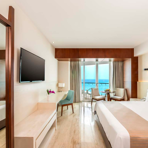 Ocean view hotel room with king bed, desk, and balcony. DEMO 3