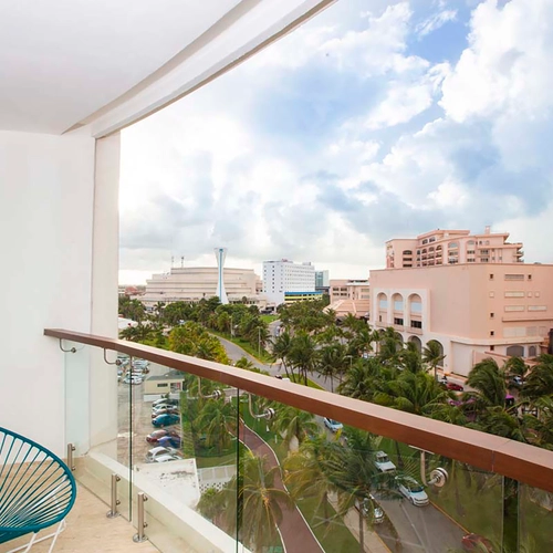 Balcony view of DEMO 3 resort with palm trees and hotel buildings.