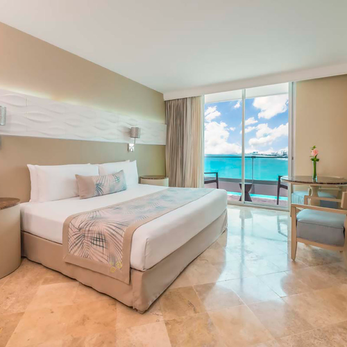 Luxury hotel room with ocean view, king bed, balcony, and comfortable seating. DEMO 3