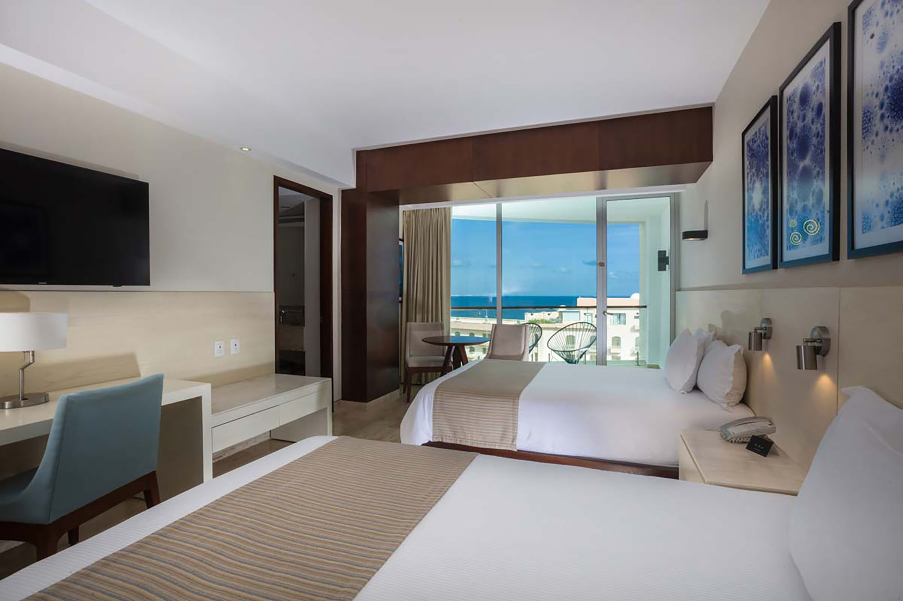 Ocean view hotel room with two beds, desk, and balcony. DEMO 3