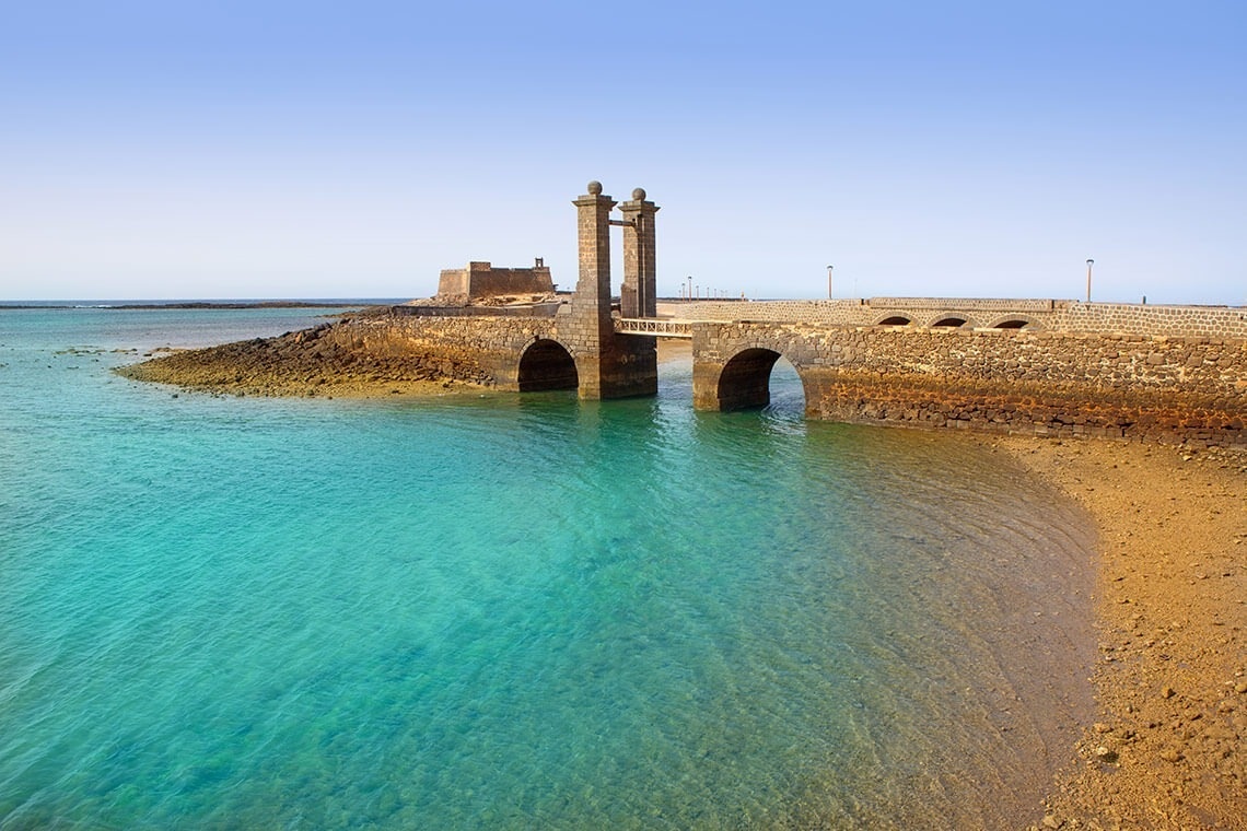 a bridge over a body of water with a castle in the background