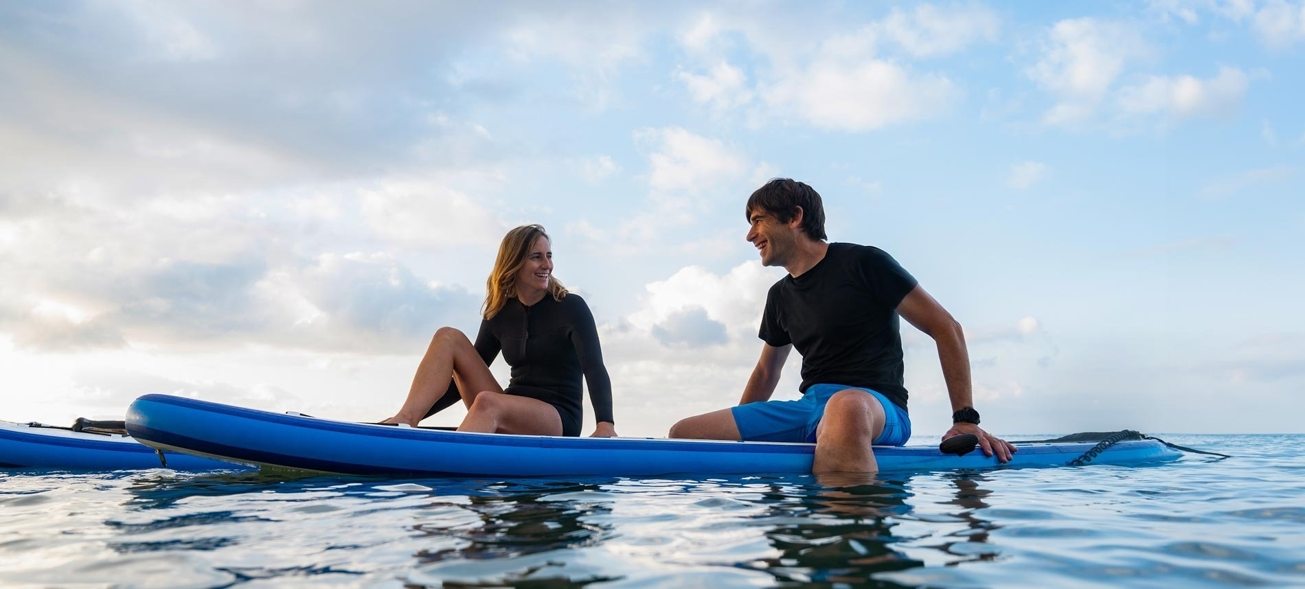 a man and a woman sit on a surfboard in the ocean