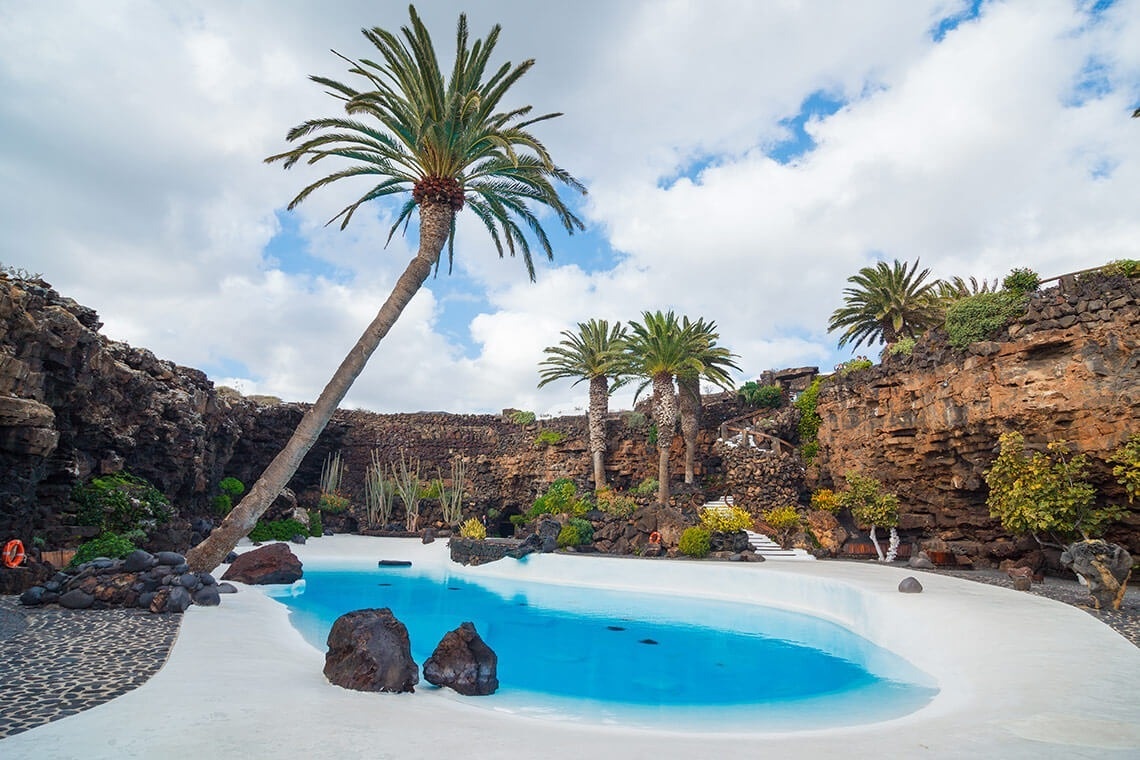 a swimming pool surrounded by rocks and palm trees