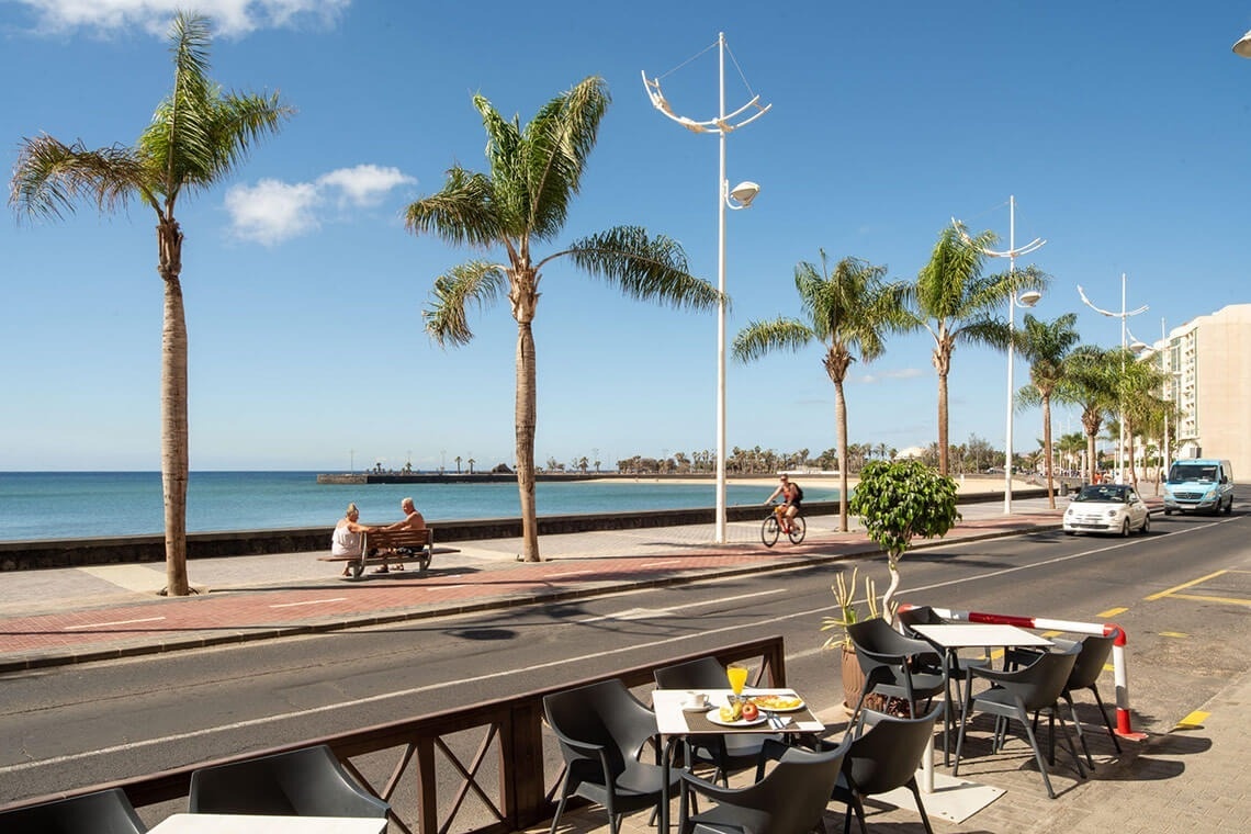 a man riding a bike down a street with tables and chairs