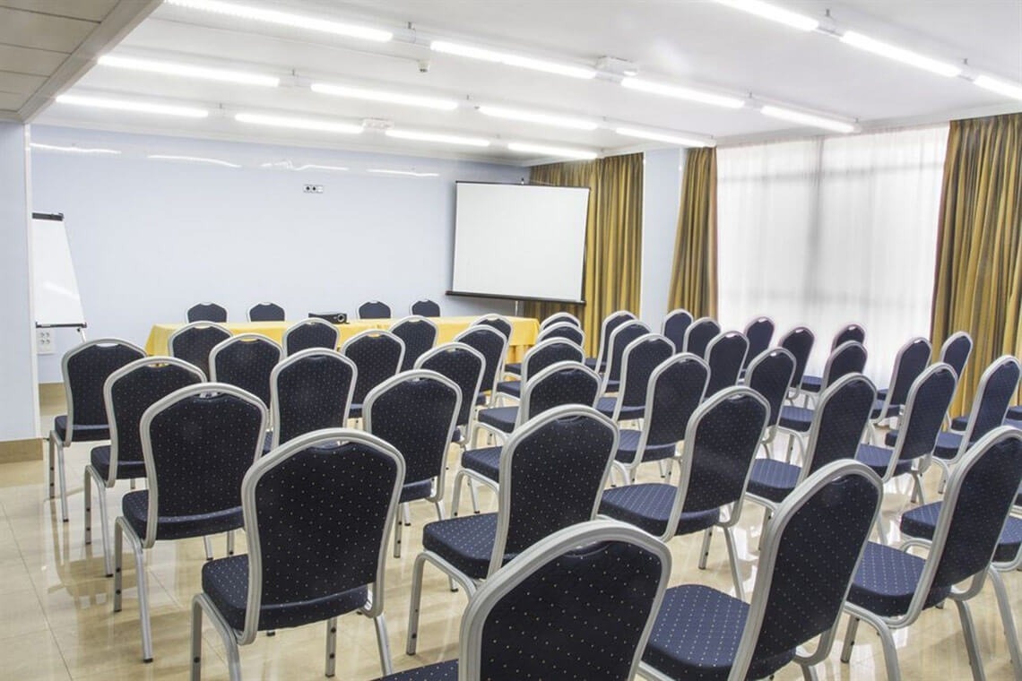 a conference room with rows of chairs and a projector screen