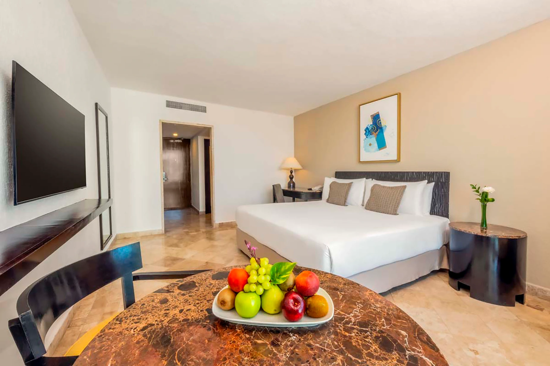 Luxurious hotel room with a king-size bed, desk, and fruit platter. DEMO 3