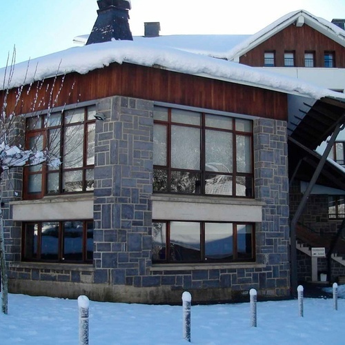 un bâtiment en pierre avec un toit en bois couvert de neige