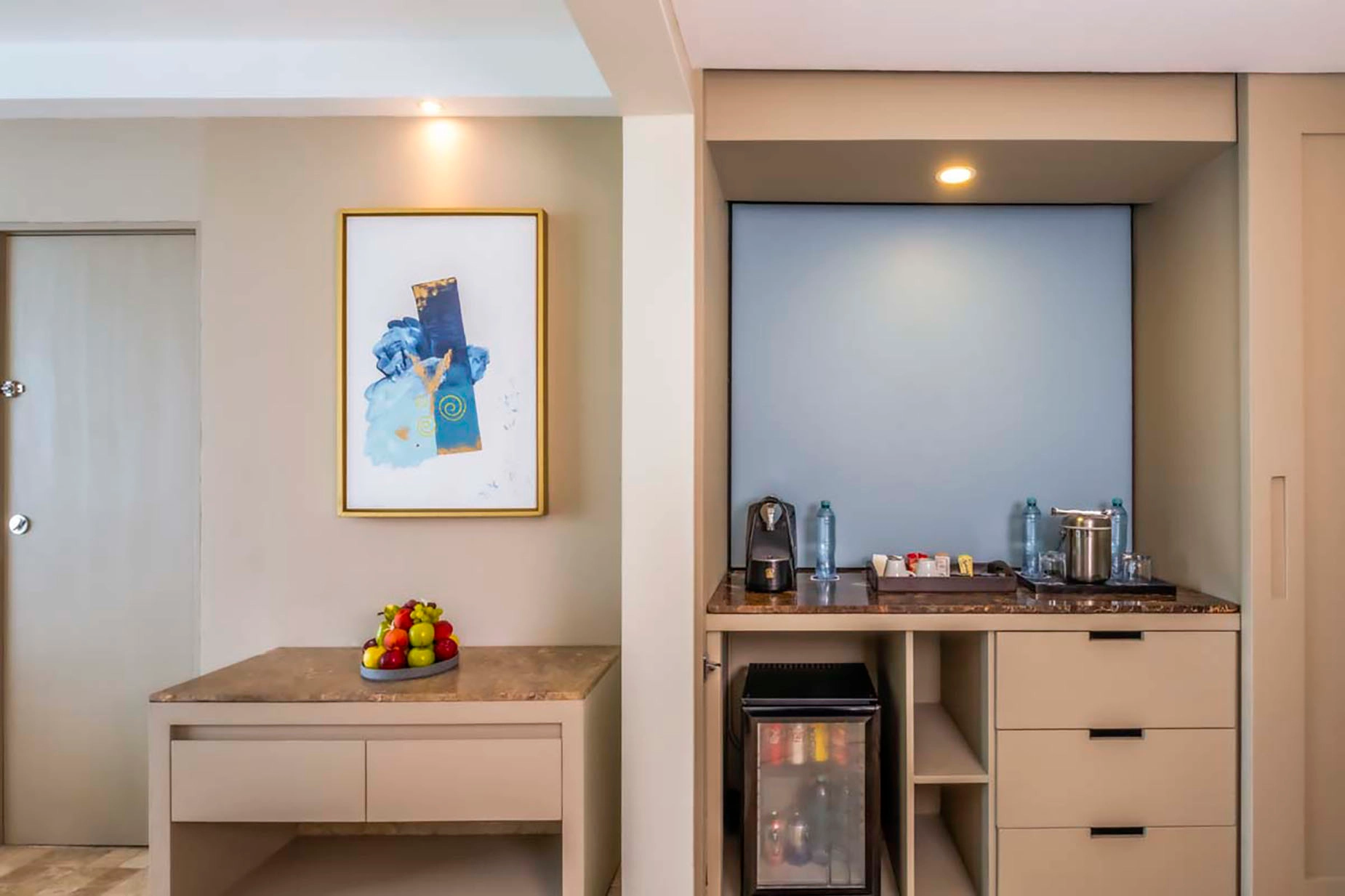 Hotel room amenities: fruit bowl, artwork, mini-bar, coffee maker, and bottled water. DEMO 3