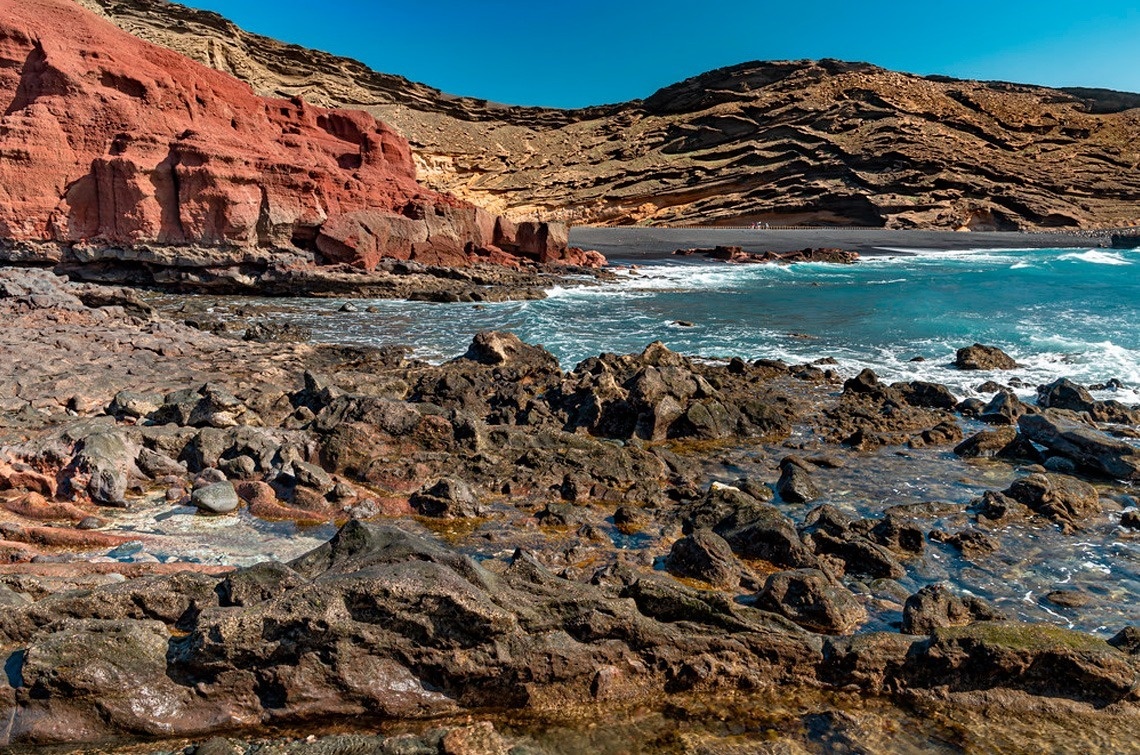 a rocky shoreline with a mountain in the background