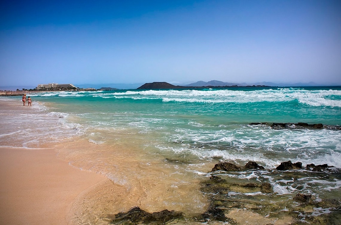 a couple standing on a beach looking at the ocean