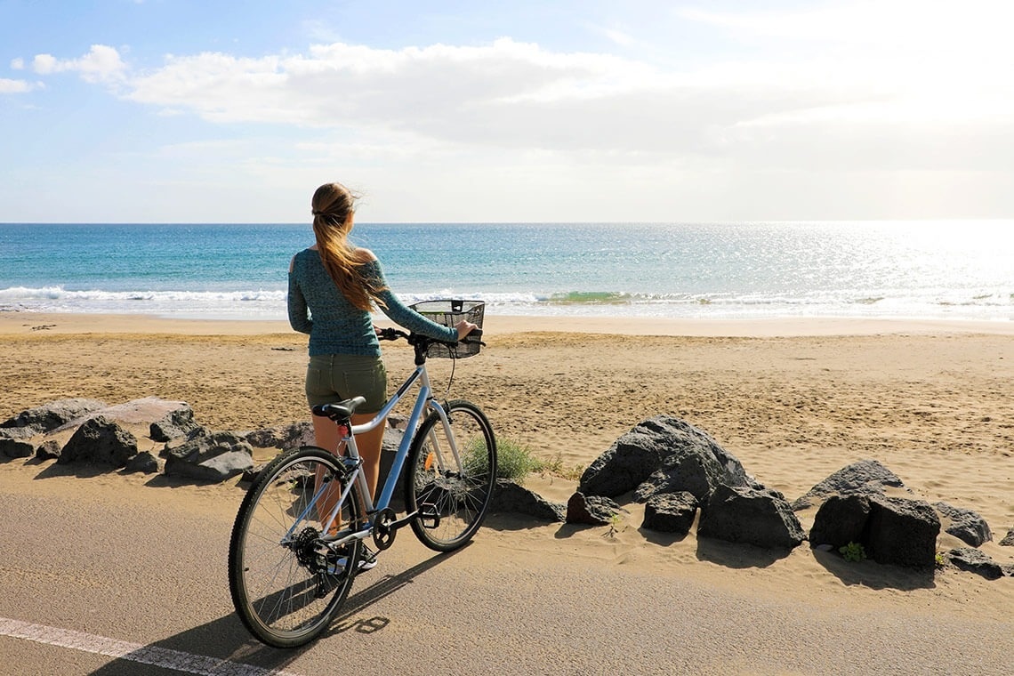 una mujer con una bicicleta mirando el océano