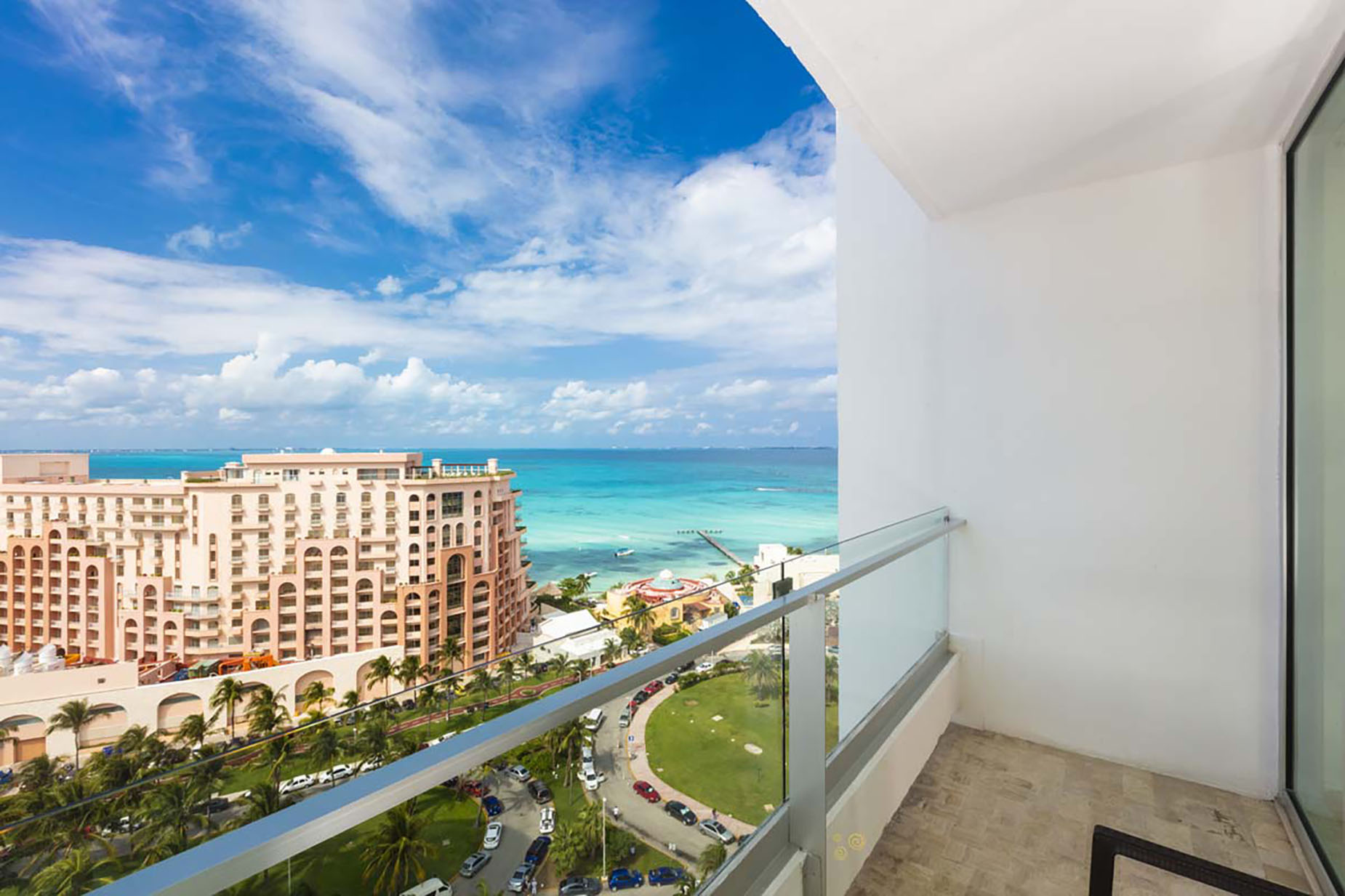 Balcony view of a tropical resort with turquoise ocean, palm trees, and an DEMO 3 hotel.
