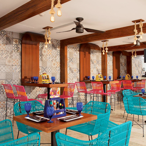 Vibrant dining area with turquoise chairs, wooden tables, and colorful tile accents at a DEMO 3.