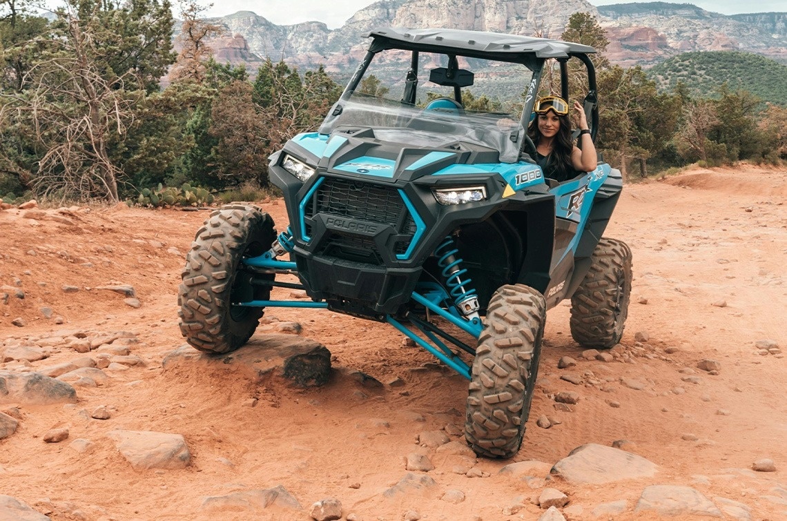 a woman is riding a polaris atv on a rocky trail