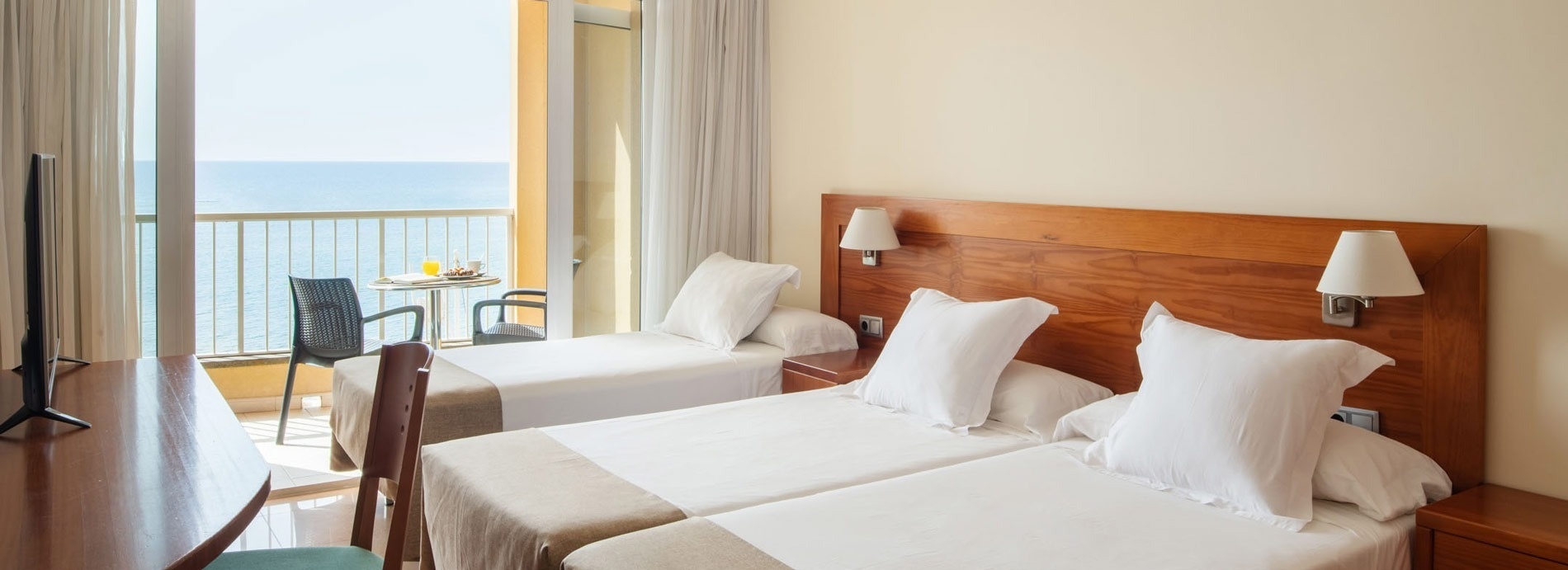 a hotel room with two beds and a balcony overlooking the ocean