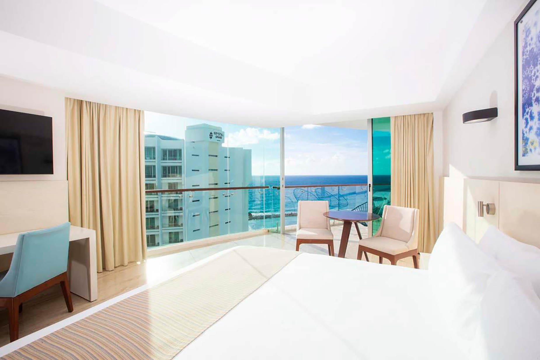 Hotel room with ocean view balcony, desk, and comfortable bed. DEMO 3