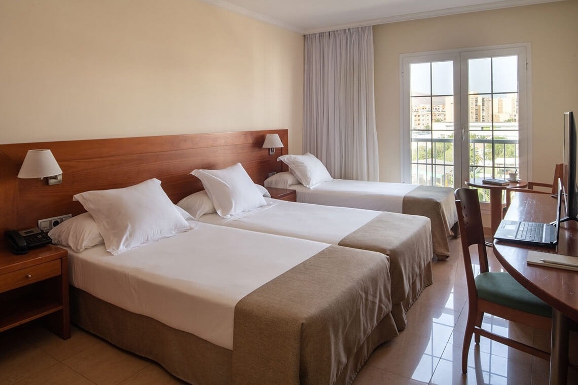 a hotel room with two beds and a desk with a laptop on it