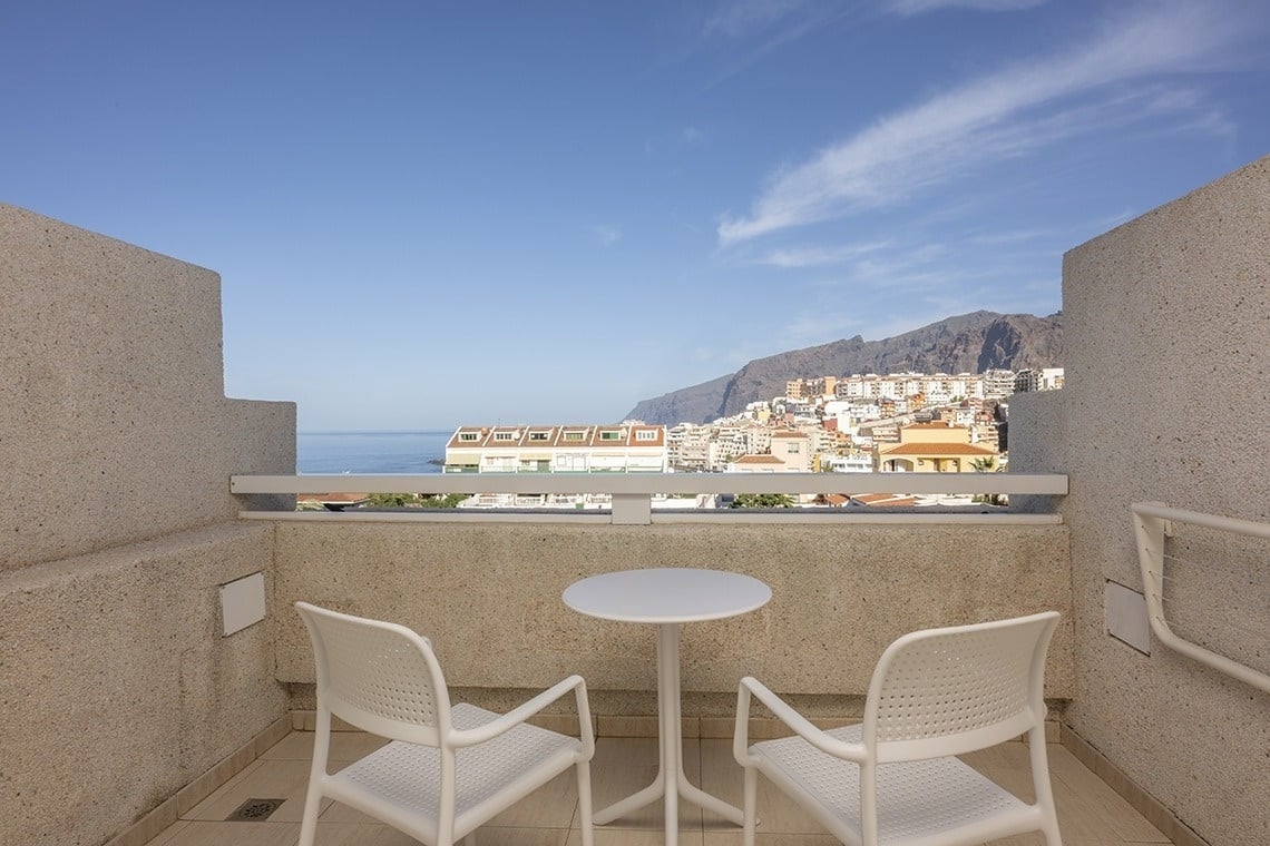 two chairs and a table on a balcony overlooking the ocean