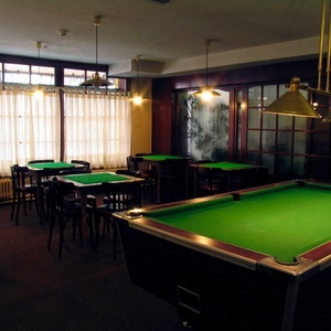 una mesa de billar en una habitación llena de mesas y sillas