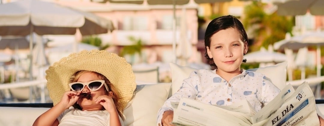 a boy and a girl sit on a couch reading el dia