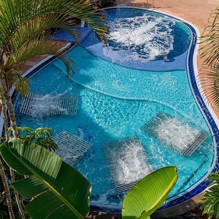 ein großer Swimmingpool umgeben von Palmen und Liegestühlen