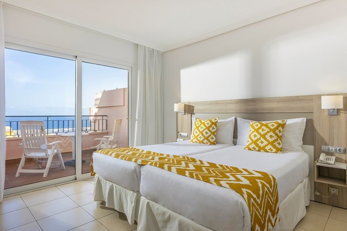 une chambre d' hôtel avec deux lits et une fenêtre avec vue sur l' océan