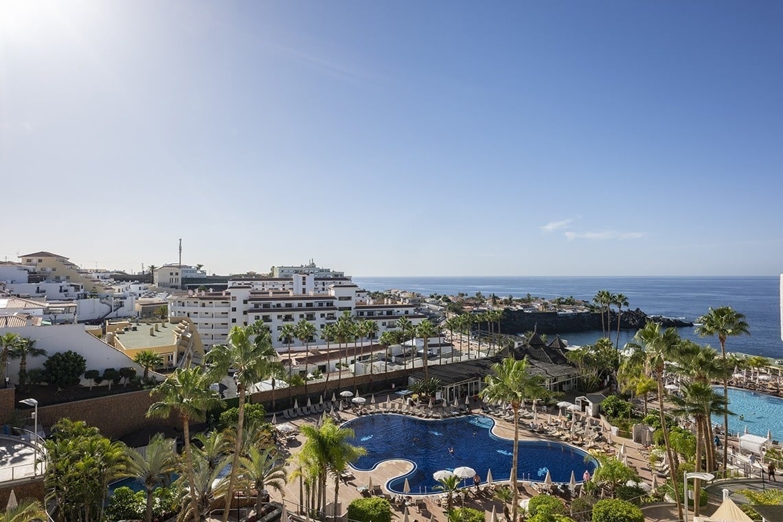 an aerial view of a resort with palm trees and a large pool