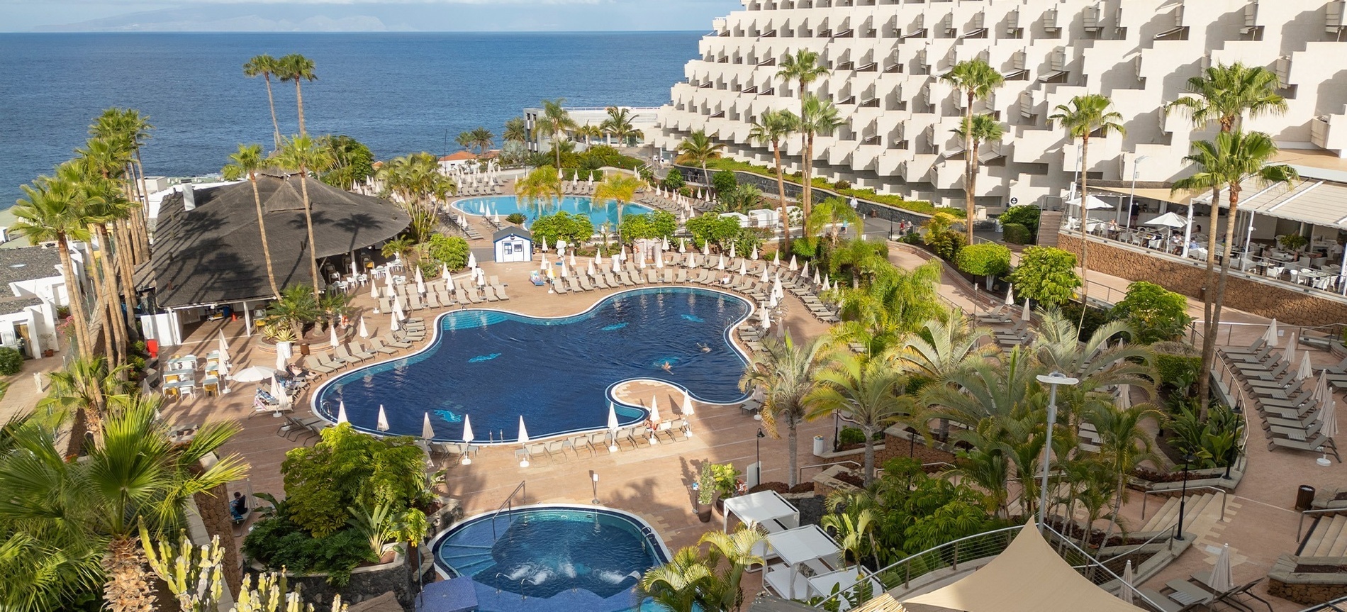 a large swimming pool surrounded by white umbrellas and chairs