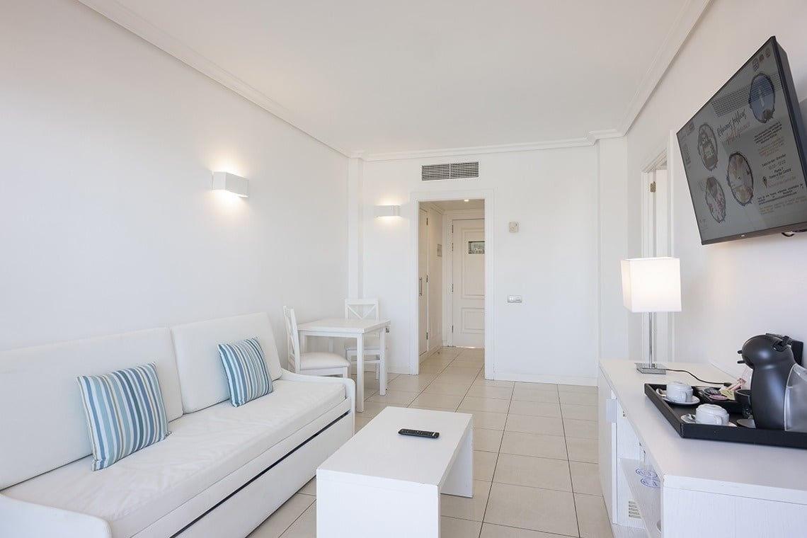 un salon blanc avec un canapé et une télévision