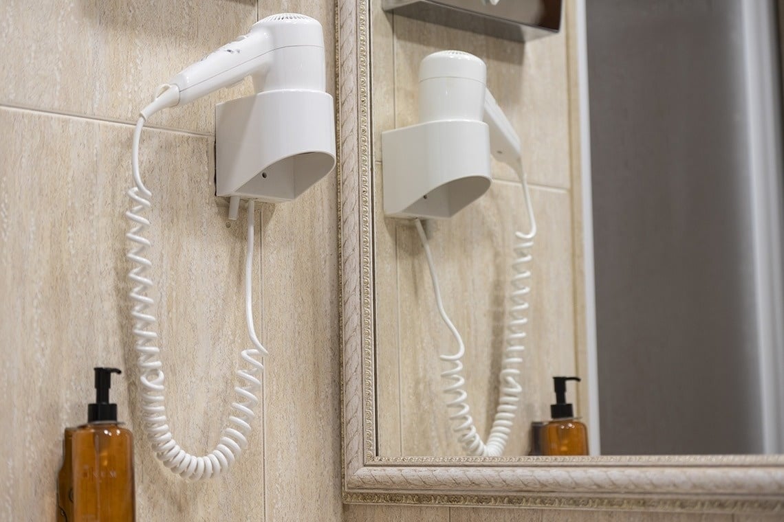 a hair dryer is hanging on a wall next to a mirror