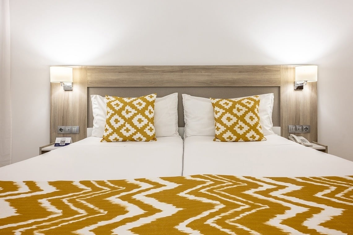 un lit d' hôtel avec des oreillers jaunes et blancs