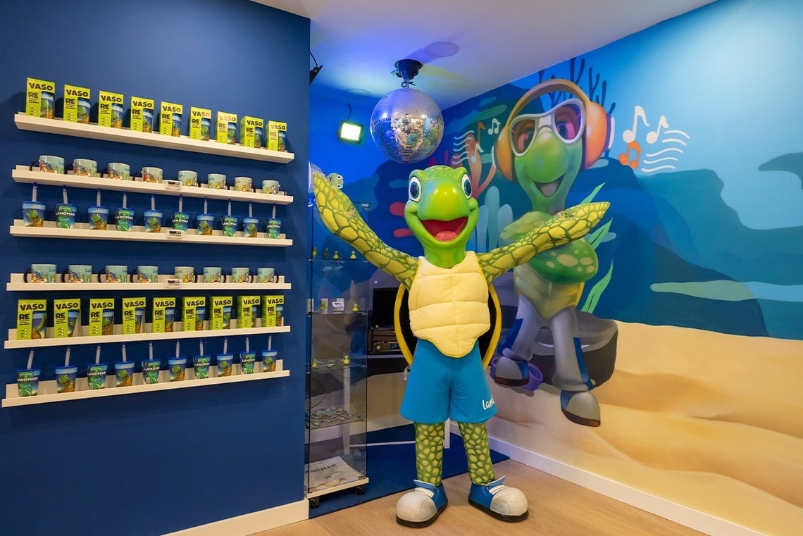 una tortuga de dibujos animados está parada frente a un estante de vasos con pajitas