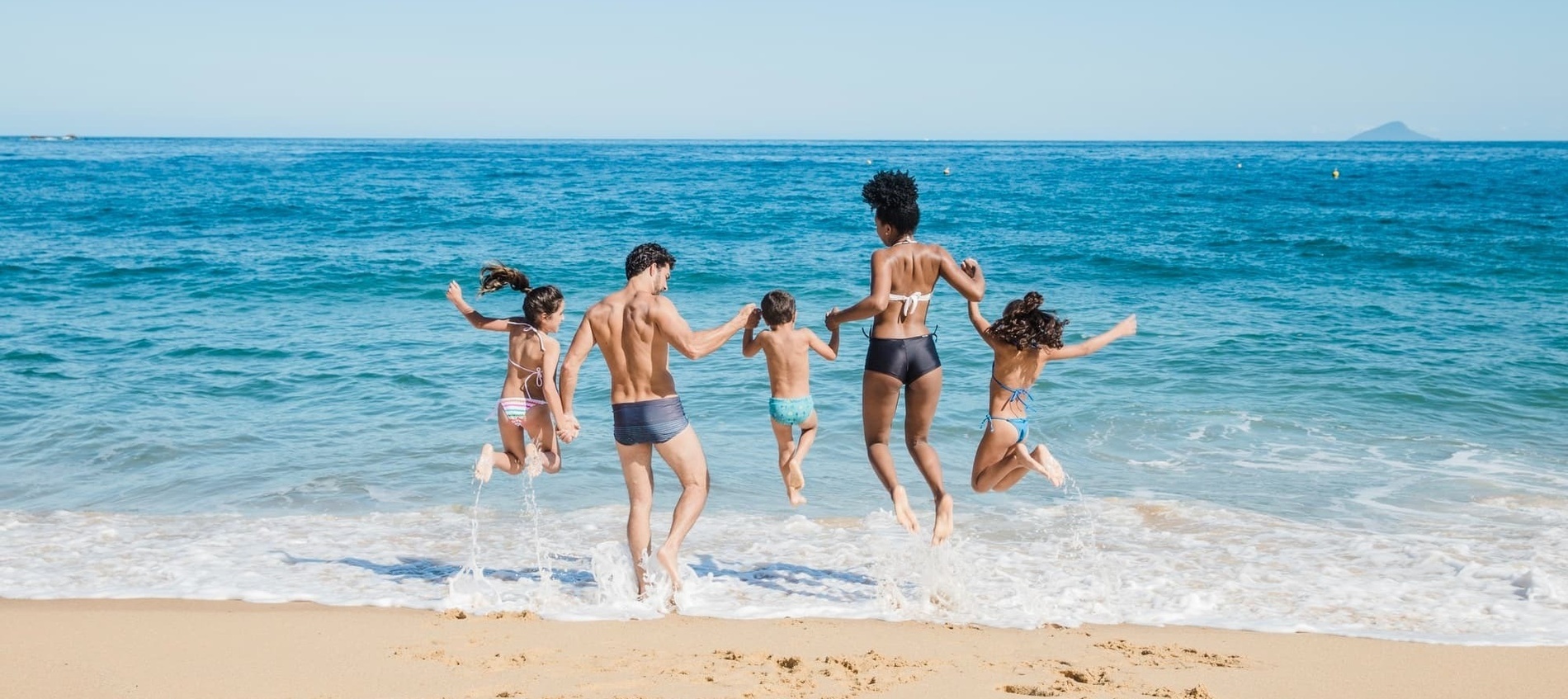 une famille saute dans l' eau sur la plage