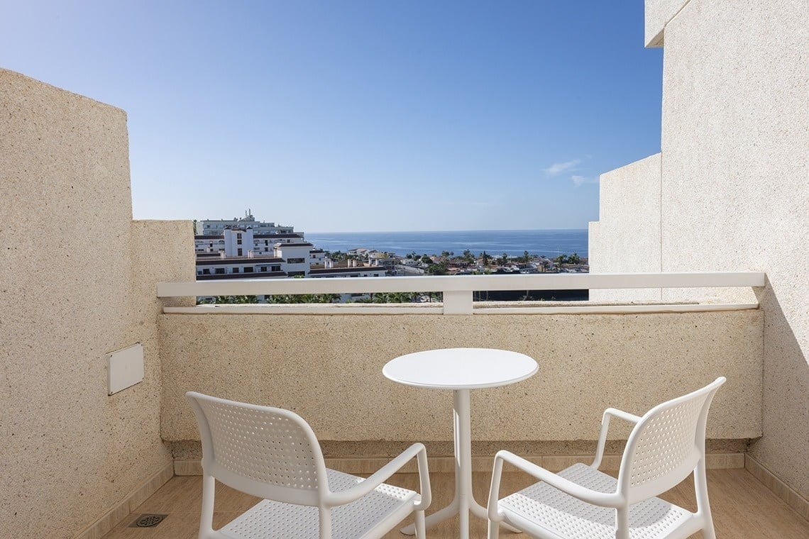 a balcony with two chairs and a table overlooking the ocean