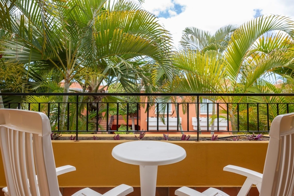 deux chaises et une table sur un balcon avec des palmiers en arrière-plan